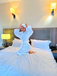 a woman in a robe sitting on a bed at TH BonRoyal Hotel in Addis Ababa