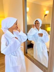 a woman in a robe looking in a mirror at TH BonRoyal Hotel in Addis Ababa