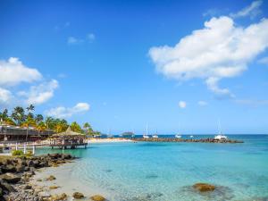 a beach with a pier and boats in the water at Le Domaine de l'Anse Mitan in Les Trois-Îlets