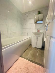 Lovely 1 bedroom apartment in London في لندن: حمام مع حوض أبيض ومغسلة