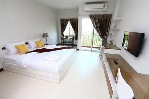 a white bedroom with a large bed and a television at Smart Mansion in Min Buri