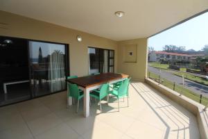 a balcony with a wooden table and green chairs at Saints View Resort Unit 9 in Uvongo Beach
