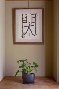 a plant sitting on a table with a picture on the wall at Tabiyu Abrigo in Kobe