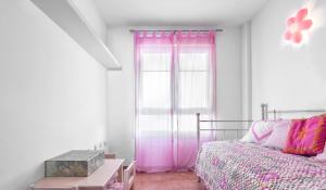 a bedroom with a bed and a window with pink curtains at Dúplex Playa in San José