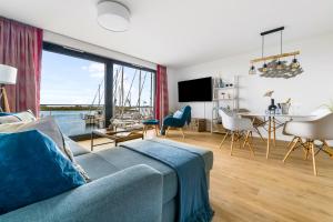 a living room with a blue couch and a large window at Hafenquartier No5 in Heiligenhafen
