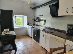 a kitchen with white cabinets and a black dishwasher at Vicario etxea in Concha