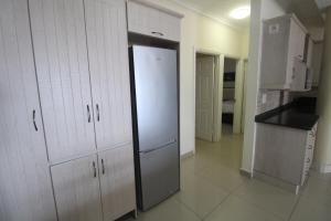 a kitchen with white cabinets and a refrigerator at Saints View Resort Unit 12 in Uvongo Beach