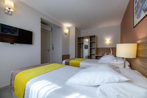 a hotel room with two beds and a flat screen tv at Residence de Tourisme Ajaccio Amirauté in Ajaccio