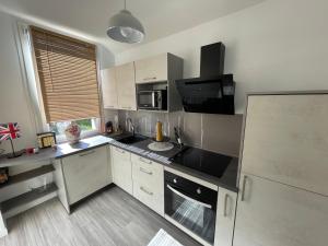 a kitchen with white cabinets and a black counter top at À la maison in Saint-Étienne