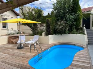 - une piscine dans un jardin avec une table, des chaises et un parasol dans l'établissement À la maison, à Saint-Étienne