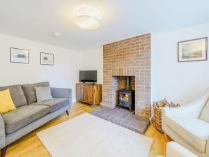 a living room with a couch and a fireplace at Branthwaite Cottage in Caldbeck