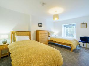 a bedroom with two beds and a dresser at Branthwaite Cottage in Caldbeck