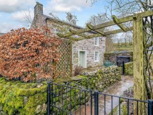 an old stone house with a gate and a stone wall at Branthwaite Cottage in Caldbeck