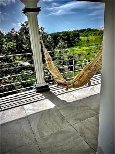 a hammock on a balcony with a view of a hill at Plumeria Hébergement Tiare in Grand-Bourg