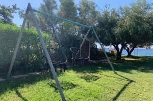 an empty swing set in the grass near the water at One Step Ι Seaside Ι Quiet Ι Green in Yerakiní