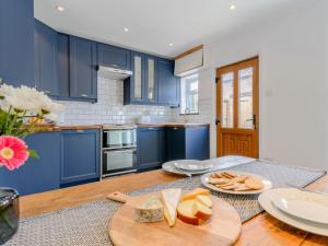 a kitchen with blue cabinets and a table with cheese at The Old Post Office in Baldersby
