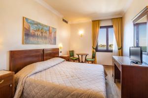 sypialnia z łóżkiem, biurkiem i telewizorem w obiekcie Hotel Panorama w Lido di Venezia