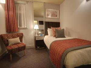 a hotel room with a bed and a chair at The Suffolk Hotel in Haverhill