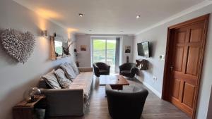 a living room with a couch and chairs and a table at Beachcombers Apartments in Newquay