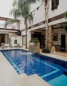 una piscina con palmeras y un edificio en Hotel Patrimonial by Greenfield en Guayaquil