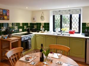 a kitchen with green cabinets and a table with chairs at Barn Court Cottage in Washfield
