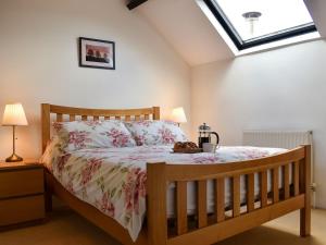 a bedroom with a wooden bed and a skylight at Barn Court Cottage in Washfield