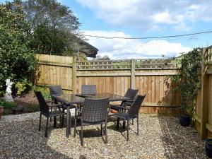 a patio with a table and chairs and a fence at Barn Court Cottage in Washfield