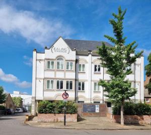 a white building with a tree in front of it at Roomspace Serviced Apartments- Walpole Court in Ealing