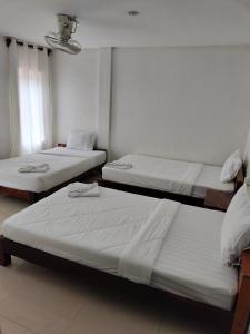 três camas num quarto com paredes brancas em city inn hotel em Siem Reap