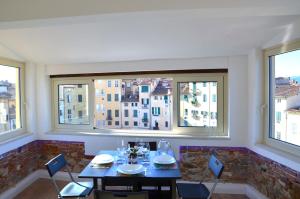 ein Esszimmer mit einem Tisch, Stühlen und Fenstern in der Unterkunft Caesar's luxury apartment in Lucca Center town Roman Amphitheater in Lucca