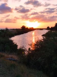 a sunset over a river with the sun reflecting on the water at Superbe appartement en rez-de-jardin à LANTON in Lanton