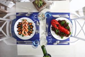 帕爾馬海灘的住宿－帕爾馬灣伊波索爾酒店- 僅限成人，一张桌子,上面放着两盘食物和一瓶葡萄酒