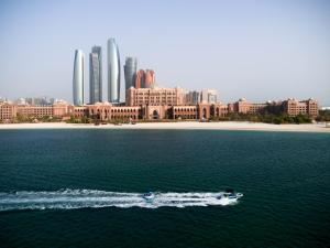 un barco en el agua frente a una ciudad en Emirates Palace Mandarin Oriental, Abu Dhabi, en Abu Dabi