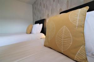 a bedroom with two beds and a pillow with leaves on it at Signature - Carnoustie House in East Kilbride
