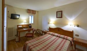 una habitación de hotel con una cama y un escritorio en Hotel Abat Cisneros Montserrat, en Montserrat