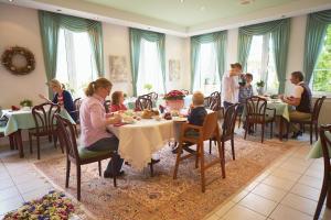 un grupo de personas sentadas en mesas en un restaurante en Landhaus Bisping, en Everswinkel