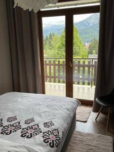 a bedroom with a bed and a view of a balcony at Apartament Cud Miód in Kościelisko