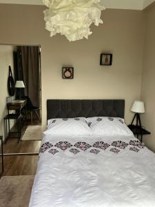a bedroom with a bed with white sheets and a chandelier at Apartament Cud Miód in Kościelisko