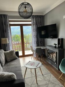 a living room with a couch and a tv at Apartament Cud Miód in Kościelisko