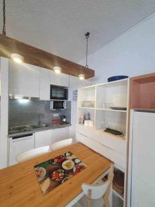 uma cozinha com uma mesa de madeira e armários brancos em SkiinSkiout Wifi Guardaesquís y Relax TETRAS em Pas de la Casa