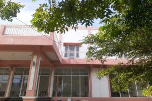 un bâtiment rose avec un balcon en haut. dans l'établissement EXPRESS O 91662 Kost Rumah Kaca, à Mirue