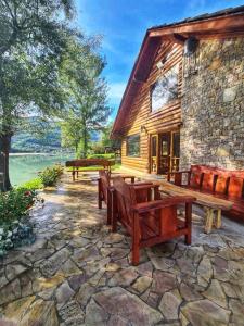 a stone patio with benches and a log cabin at Villa California in Rezine