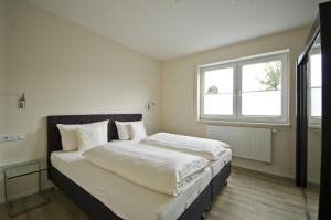 a bedroom with a bed with white sheets and a window at Appartements Am Kurpark in Bad Windsheim