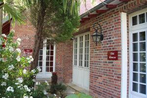 Les Jardins Carnot في كومبيان: منزل من الطوب مع أبواب بيضاء وعلامة عليه
