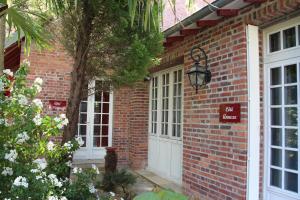 une maison en briques dotée de portes blanches et d'un panneau. dans l'établissement Les Jardins Carnot, à Compiègne