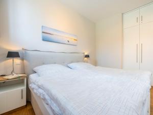 a white bedroom with a white bed and a desk at Ferienappartement MEERZEIT in Mursewiek