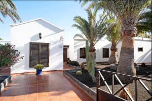 a courtyard with palm trees and a white house at Villa Las Palmeras in Playa Blanca