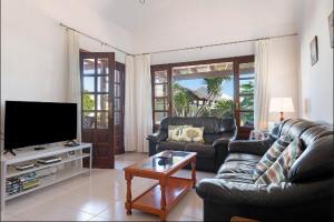 a living room with two couches and a flat screen tv at Villa Las Palmeras in Playa Blanca