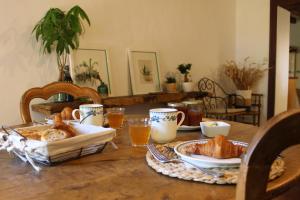 a table with a breakfast of bread and orange juice at LE DOMAINE DU PETIT TERTRE - SPA EN EXTERIEUR in Saint-Jean-dʼAssé