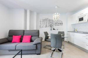 Vegueta Luxury Apartments في لاس بالماس دي غران كاناريا: غرفة معيشة مع أريكة وطاولة مع وسائد وردية
